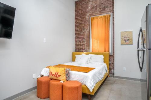 a bedroom with a bed with two orange ottools at The Davis Lofts at Main Street - Unit 1E in Rocky Mount