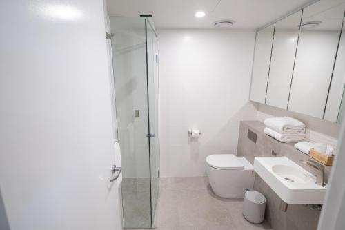 a bathroom with a shower and a toilet and a sink at Oshen Holiday Apartments Yeppoon in Yeppoon