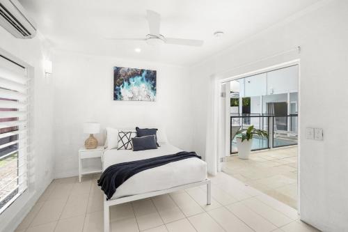 a white bedroom with a bed and a window at Belle Escapes Villa Rosa just minutes to Trinity Beach in Trinity Beach