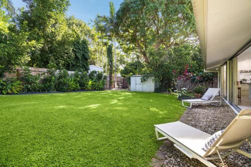 a backyard with a lawn with two chairs and a fence at Belle Escapes Villa Rosa just minutes to Trinity Beach in Trinity Beach