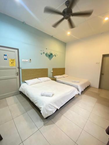 two beds in a room with a ceiling fan at Raintown inn taiping in Taiping