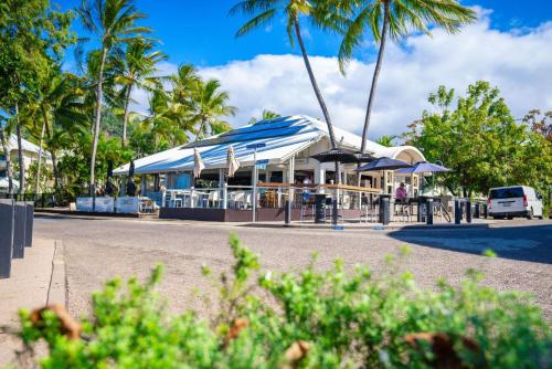 a restaurant with blue and white umbrellas and palm trees at Belle Escapes Villa Rosa just minutes to Trinity Beach in Trinity Beach