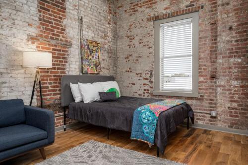 a bedroom with a bed and a chair and a brick wall at The Davis Lofts at Main Street - Unit 3D in Rocky Mount