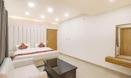 a white bedroom with a bed and a couch at FabHotel Ruklo in Patna