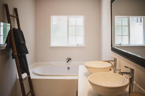 a bathroom with two sinks and a tub and a mirror at Stirling Loft in Johannesburg