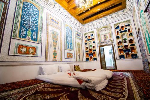 a bedroom with a large bed in a room with paintings at Zaringiz Boutique in Bukhara