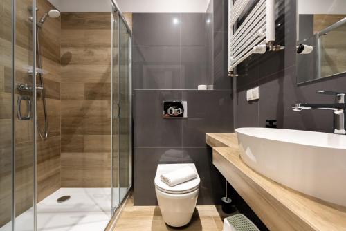 La salle de bains est pourvue de toilettes, d'un lavabo et d'une douche. dans l'établissement Apartamenty Laguna Beskidów 46 z sauną i siłownią - Dream Apart, à Zarzecze