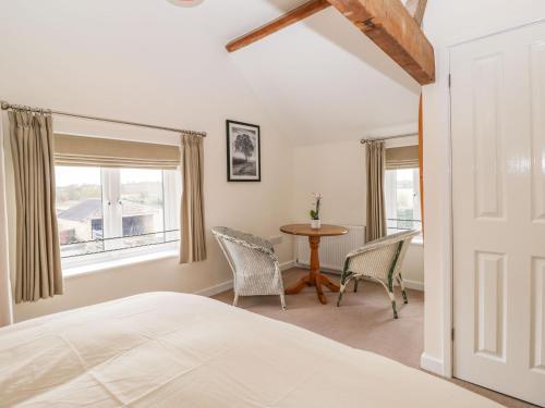 a bedroom with a bed and a table and chairs at Stables Cottage in Melksham