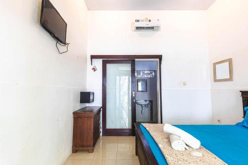 a bedroom with a bed and a television on the wall at Surf Retreat Villa Sari Bali in Pulukan