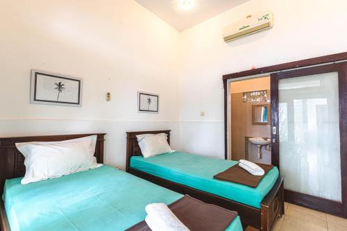 a room with two beds and a chair in it at Surf Retreat Villa Sari Bali in Pulukan