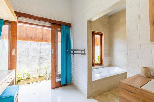 a bathroom with a bath tub and a window at Surf Retreat Villa Sari Bali in Pulukan