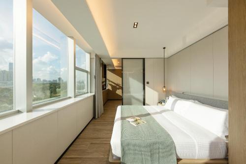 CM Serviced Apartment Shenzhen Dongmen في شنجن: غرفة نوم بسرير كبير ونوافذ كبيرة