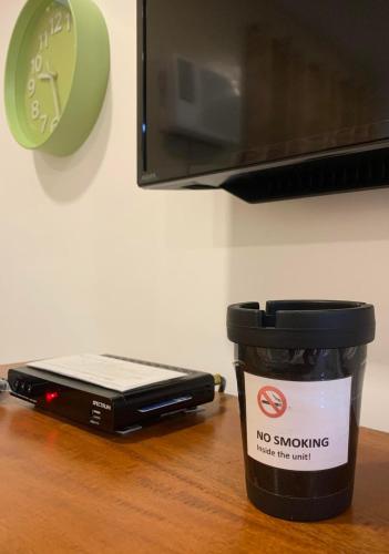 a coffee cup with a no smoking sign next to a microwave at JORA Studio Apartment 1-C in Dagupan