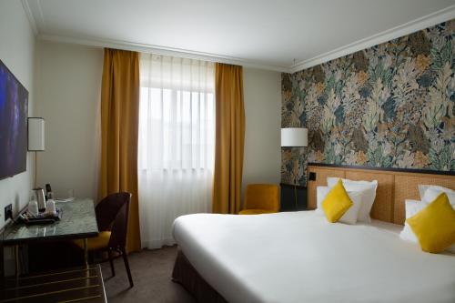 a hotel room with a large bed and a desk at Hotel Paris Boulogne in Boulogne-Billancourt