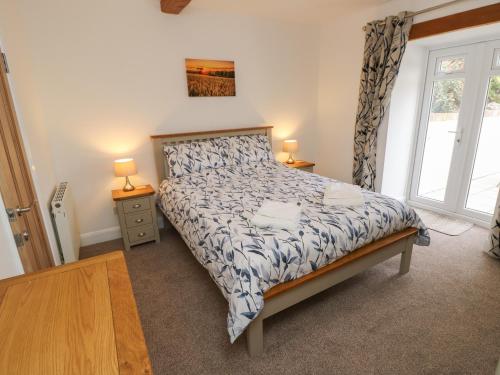 a bedroom with a bed and two lamps and a window at Dairy Cottage in Newport