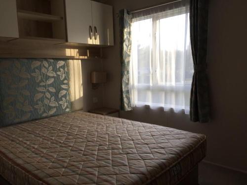 une chambre avec un grand lit avec une fenêtre dans l'établissement Assist' Mobil Home Grand mobil home 3 chambres proche châteaux de la Loire AMHCH9, à Onzain