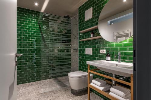 a green tiled bathroom with a sink and a toilet at Livingreen Residences in Feldkirch