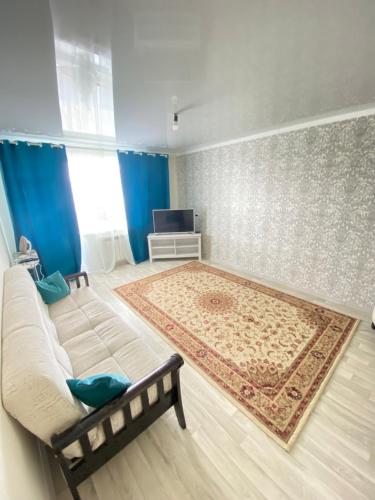 sala de estar con sofá y alfombra en 2-х комнатная квартира напротив аквапарка en Aktobe