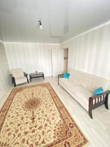 sala de estar con sofá blanco y alfombra en 2-х комнатная квартира напротив аквапарка, en Aktobe