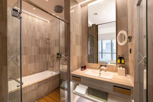 a bathroom with a sink and a tub and a shower at Nina Hotel Kowloon East in Hong Kong