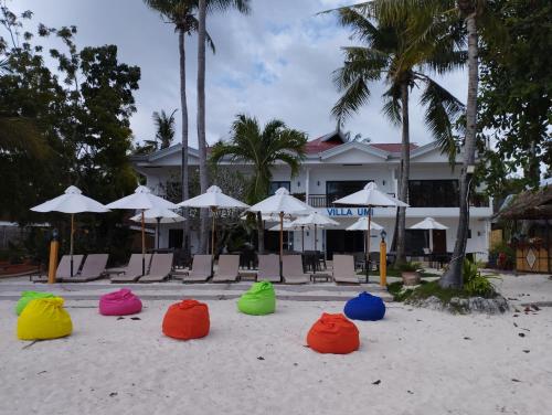 a group of colorful chairs and umbrellas on the beach at Villa Umi Panglao Resort in Panglao