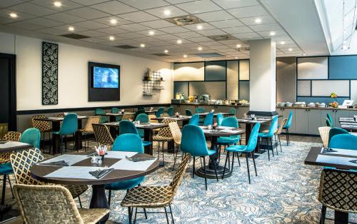 a restaurant with tables and chairs in a room at Hotel Paris Boulogne in Boulogne-Billancourt