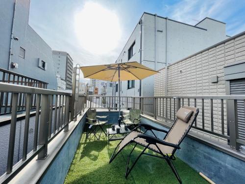 a patio with chairs and an umbrella on a balcony at Asakusa，2BR Cozy Detached House，10mins to Sensō-ji in Tokyo