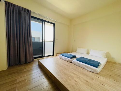 1 dormitorio con 2 camas y ventana grande en Wind Island B&B, en Hsing-wen