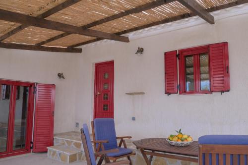 Yasemia Wood & Stone Villa في Makris Gialos: غرفة بنوافذ حمراء وطاولة وكراسي
