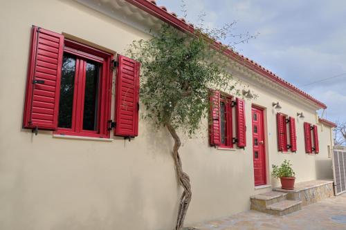 uma casa com janelas vermelhas e uma árvore em Yasemia Wood & Stone Villa em Makris Gialos