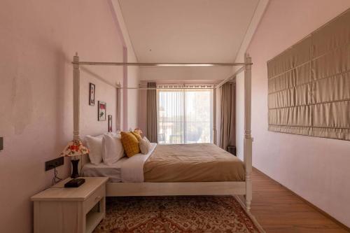 a bedroom with a canopy bed and a window at StayVista's Enchanting Haven - Modern Interiors, Sprawling Lawn with Gazebo, Swimming Pool, Indoor Games in Panchgani