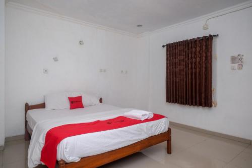 a bedroom with a bed with a red blanket on it at RedDoorz at H&W Hotel Solo in Solo