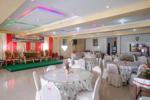 um salão de banquetes com mesas brancas e cadeiras brancas em RedDoorz at H&W Hotel Solo em Surakarta