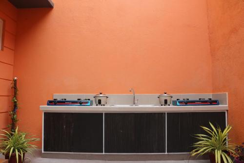 - un lavabo dans une chambre avec un mur orange dans l'établissement Anicia Guesthouse Rooms, à Manille