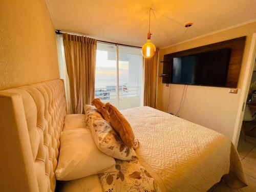 a bedroom with a bed with pillows and a television at Bello departamento Resort vista al mar in Iquique