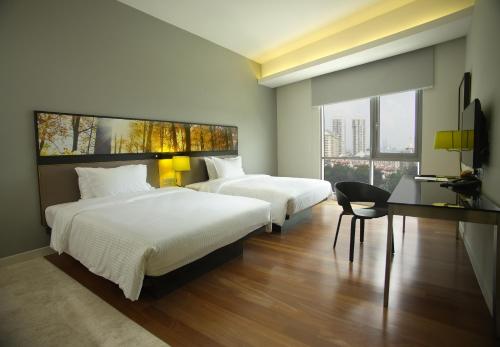 a bedroom with two beds and a table and a chair at The Signature Hotel & Serviced Suites Kuala Lumpur in Kuala Lumpur