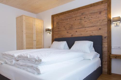 Schlafzimmer mit einem weißen Bett mit einem Kopfteil aus Holz in der Unterkunft Thorau's Lifestyle in Maria Alm am Steinernen Meer