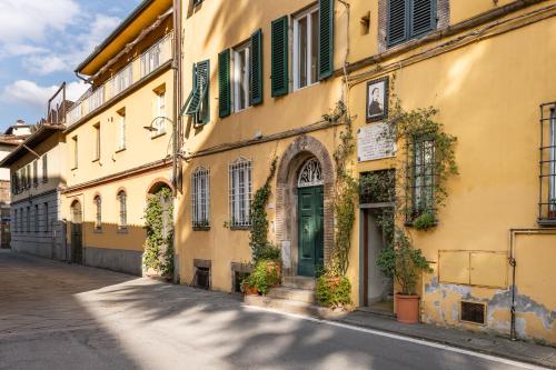 a yellow building with green shutters on a street at La terrazza di Sofia in Lucca