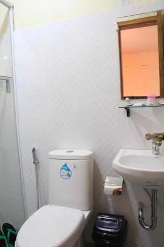 a bathroom with a white toilet and a sink at Anicia Guesthouse Rooms in Manila