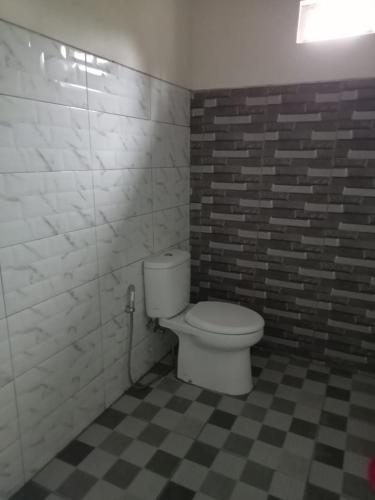a bathroom with a toilet and a checkered floor at Savana Guesthouse in Bromo