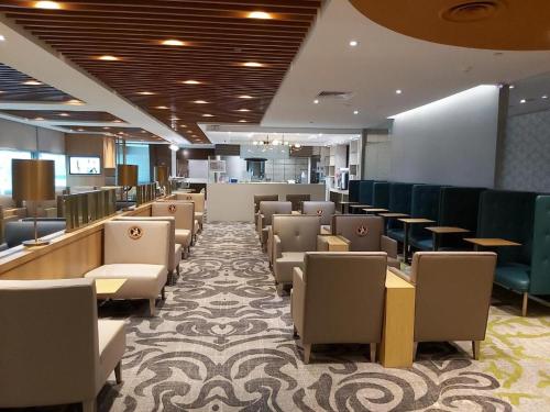 Ambassador Transit Lounge Terminal 3 في سنغافورة: غرفة انتظار مع كراسي وطاولات في مستشفى