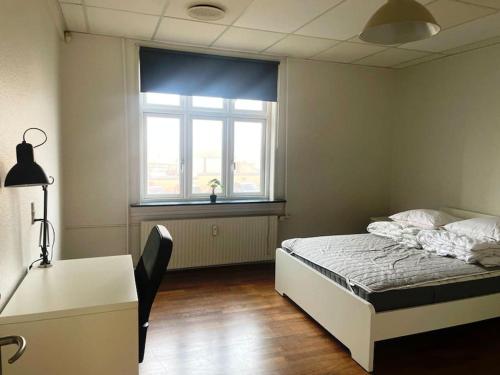 a bedroom with a bed and a desk and a window at Stor lejlighed tæt på centrum. in Viborg
