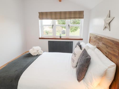 a bedroom with a white bed with two pillows at Canny Cottage in Belford