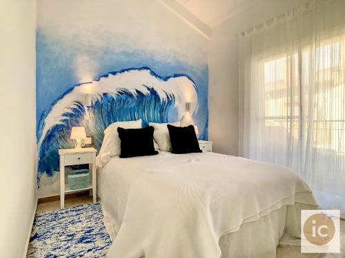 a bedroom with a large white bed with a blue painting at La Vela Estartit Rental in L'Estartit