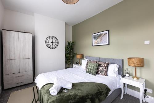 ein Schlafzimmer mit einem Bett und einer Uhr an der Wand in der Unterkunft Levi Suite by Koya Homes in Cardiff