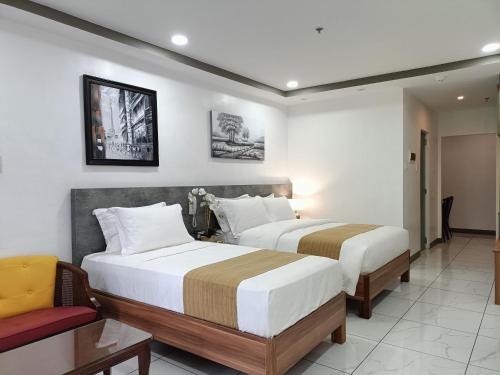 a hotel room with two beds and a chair at Rosh Hotel in Manila
