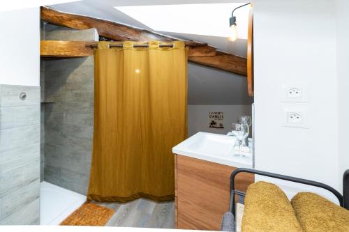 uma casa de banho com uma cortina de chuveiro amarela e um lavatório. em La Ferblanterie em Rambervillers