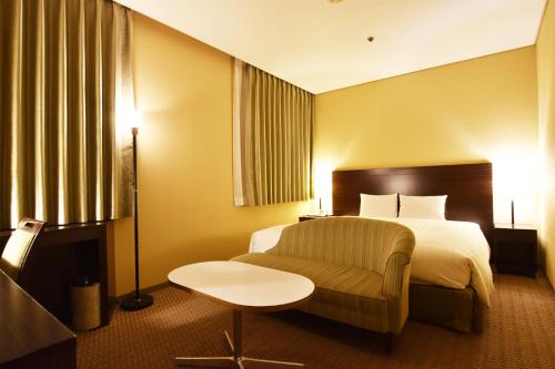 a hotel room with a bed and a chair at Hotel Nikko Tsukuba in Tsukuba