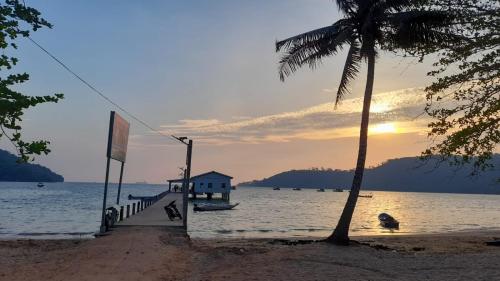 a palm tree next to a beach with the ocean at Bong's Guesthouse M'Pai Bay in Koh Rong Sanloem