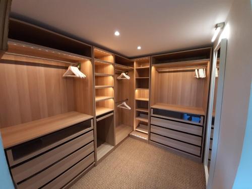 Elle comprend un dressing avec des armoires et des étagères en bois. dans l'établissement Grande maison avec piscine à Urt, proche de Bayonne - FR-1-239-653, à Urt